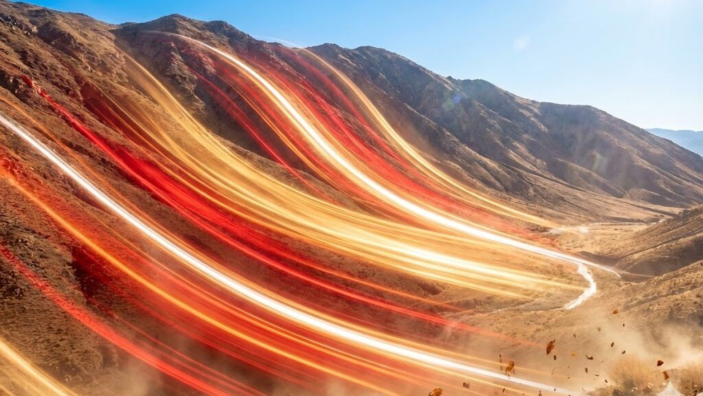 山の風下側に乾いた熱風が吹き降りるフェーン現象を暖色光で表現した実写風イメージ