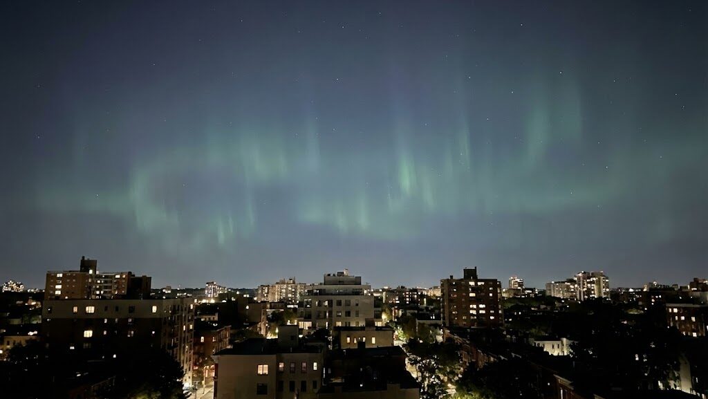 夜の街の一部が暗くなった停電イメージと、空に広がる光の揺らぎを描いた実写風画像