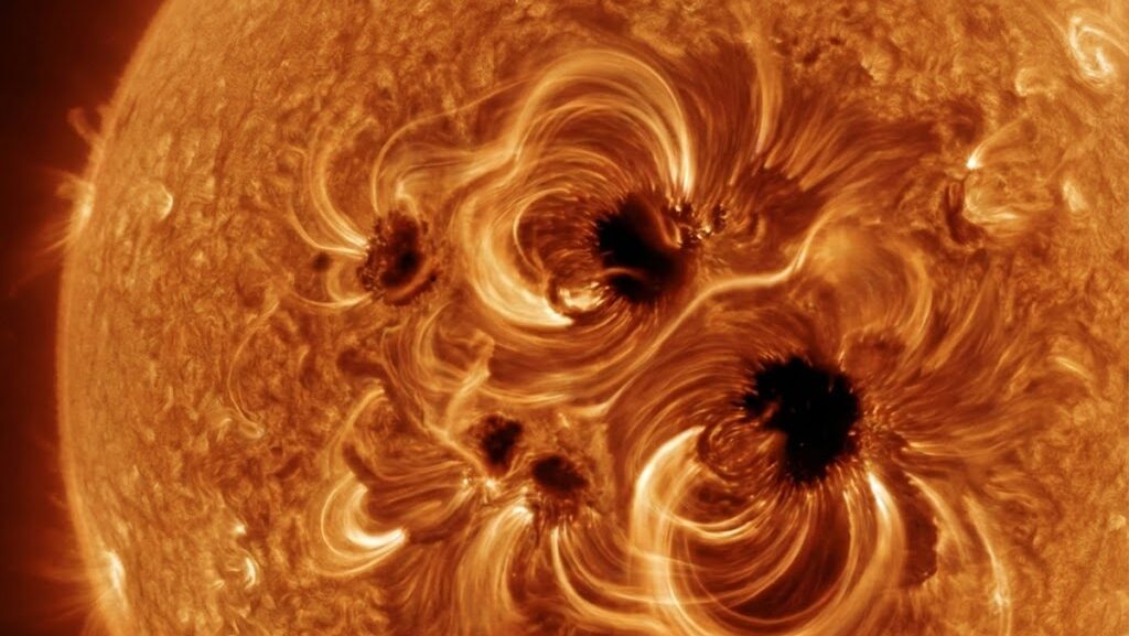 黒点が目立つ太陽表面と、磁力のねじれを抽象的に表現した太陽活動のイメージ画像