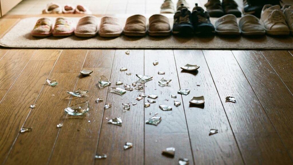 地震後の室内床に散乱したガラスと足元の危険を伝えるイメージ