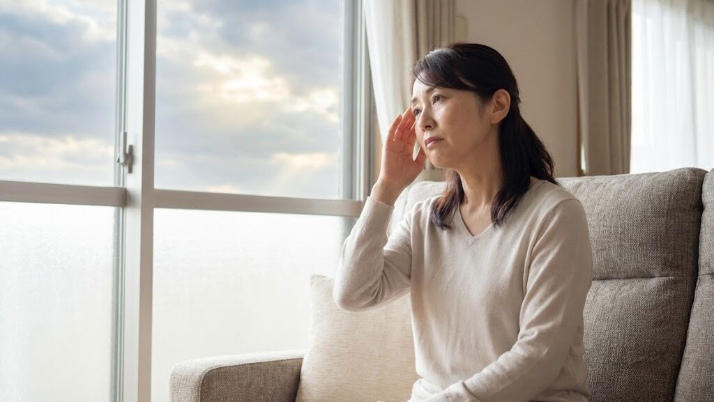台風通過中の気圧低下で体調不良を感じ、頭を押さえて休んでいる室内の様子