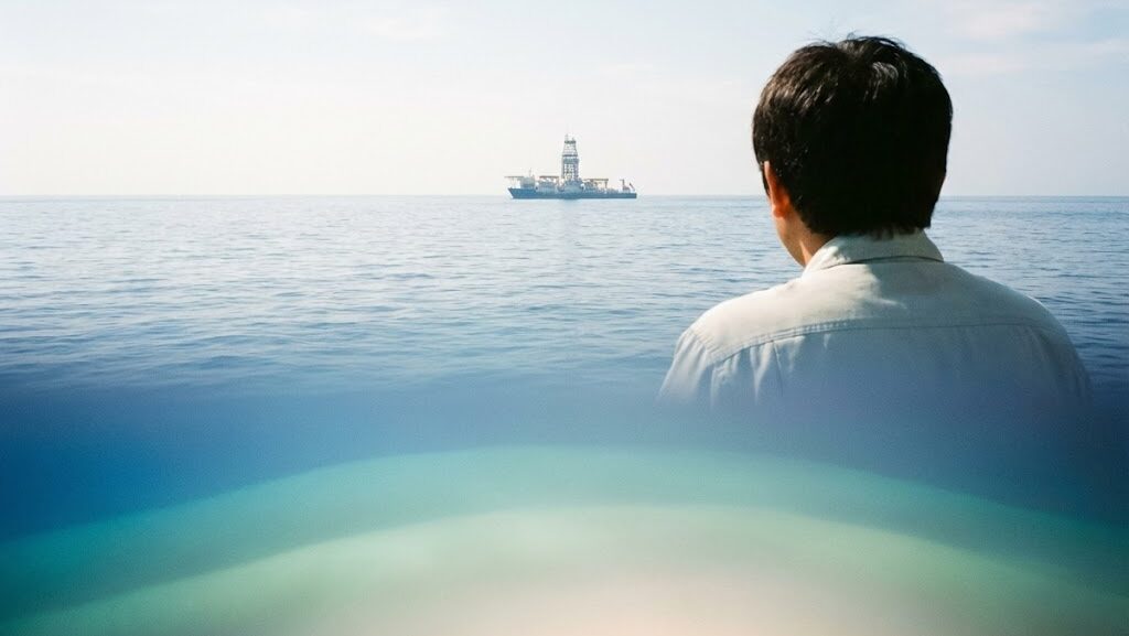 海上から地球内部を探査する船を見つめ、地震研究の最前線を感じている研究者の姿