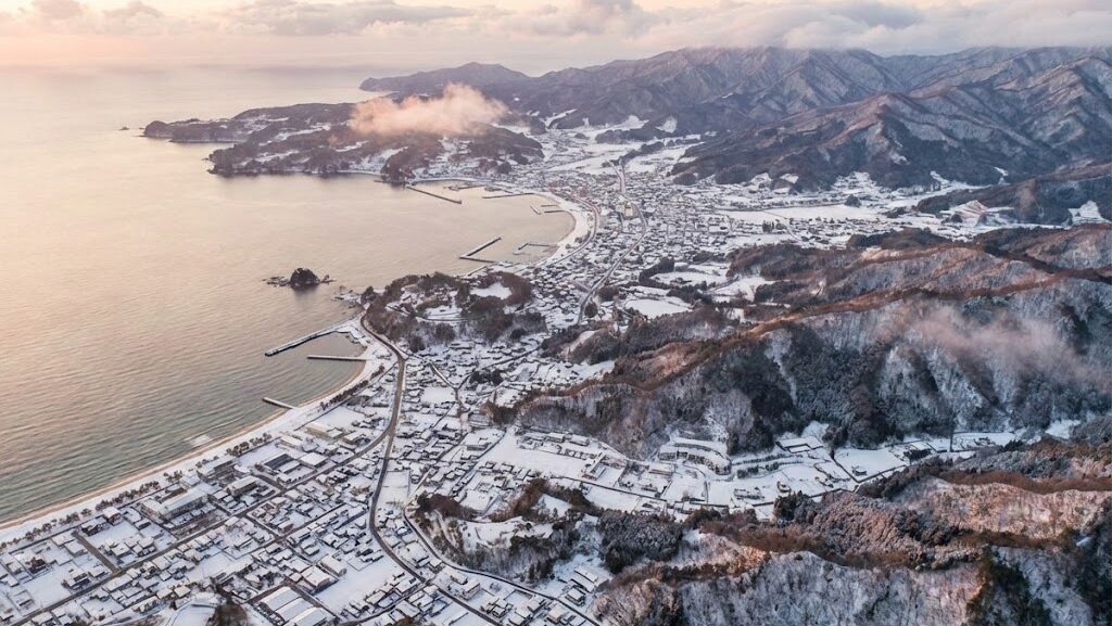 冬の日本の街並みと自然を俯瞰し、1月に起きた地震や災害の記録を象徴的に表現したイメージ