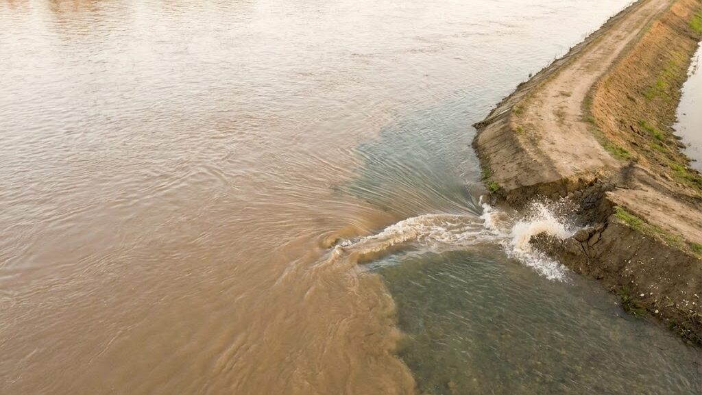 本流の水位上昇で支流の水が流れにくくなるバックウォーター現象を示す実写風イメージ