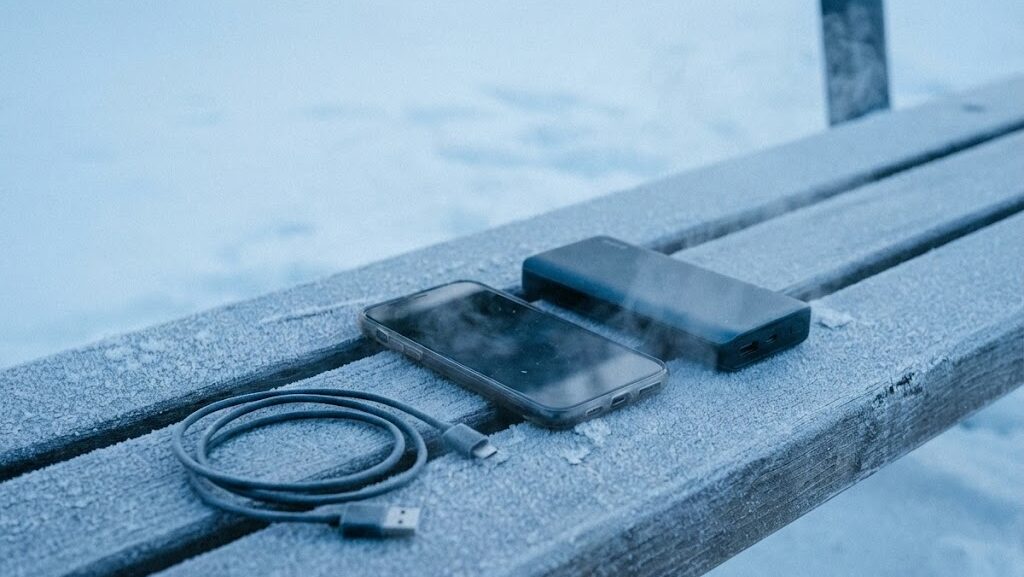冬の屋外でスマートフォンとモバイルバッテリーを並べた様子。氷点下での充電リスクを示すイメージ