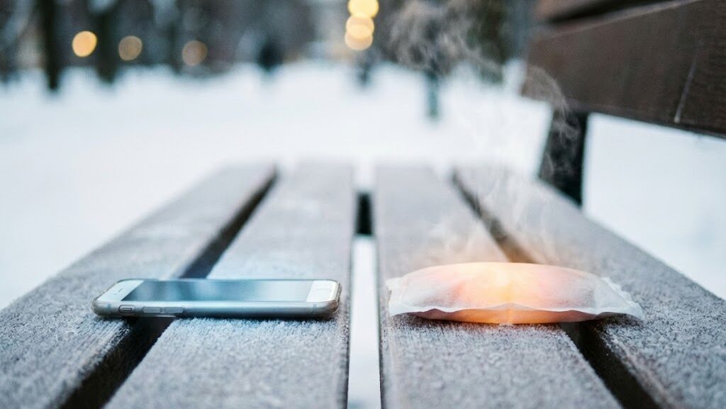 スマートフォンと使い捨てカイロが近くに置かれた様子。誤った寒さ対策の危険性を伝えるイメージ