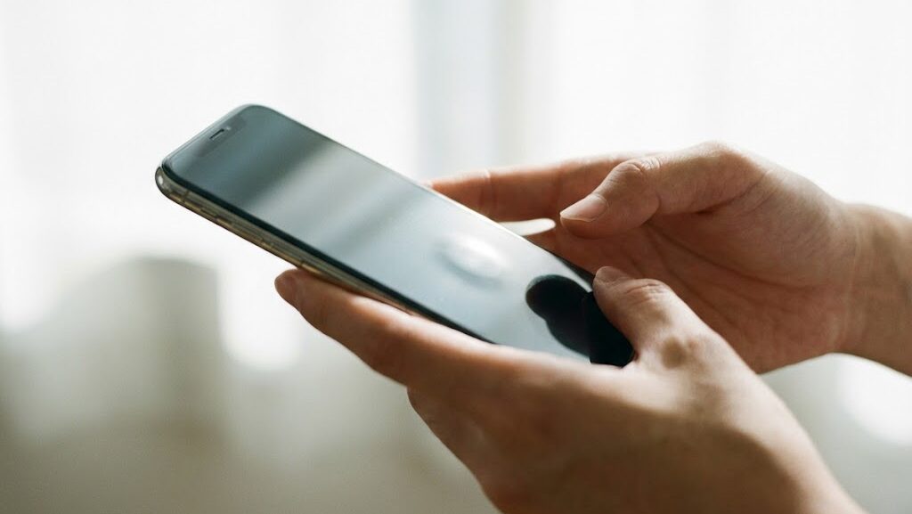 スマートフォンを横から観察する手元の写真。バッテリー劣化や異変を見分ける場面を表現