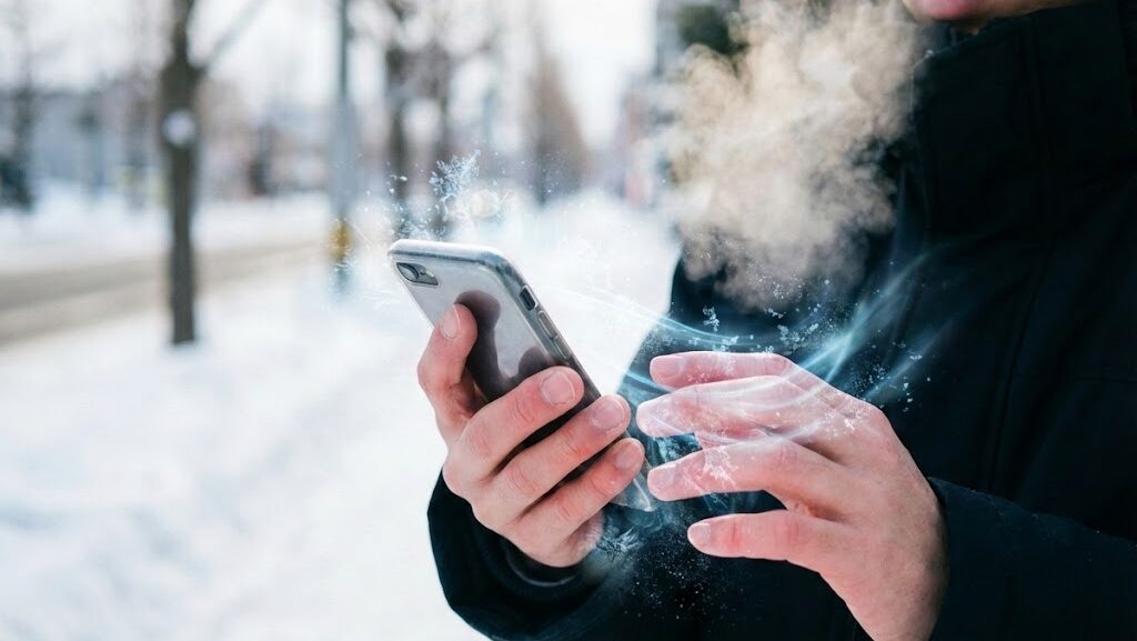 冬の寒い屋外でスマートフォンを手に持つ様子。低温環境で電池の減りが早くなる原因をイメージした写真