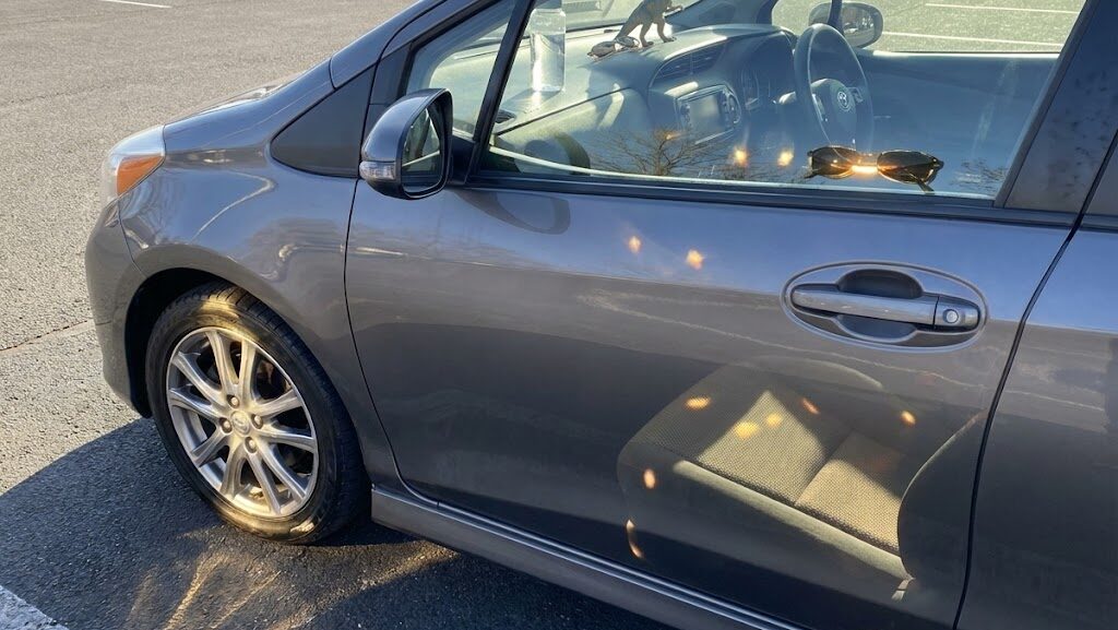 駐車中の車のホイールや車内に太陽光が反射することで起こる収れん火災リスクを表したイメージ