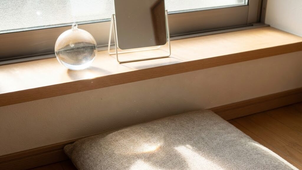 窓際に置かれた鏡やガラス製品に太陽光が反射・集中する様子を表した収れん火災の仕組みイメージ