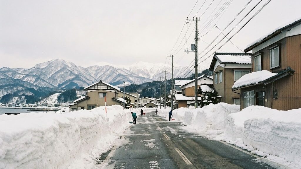 福井豪雪を思わせる日本海側の街で道路脇に高く積もった雪と冬の生活風景