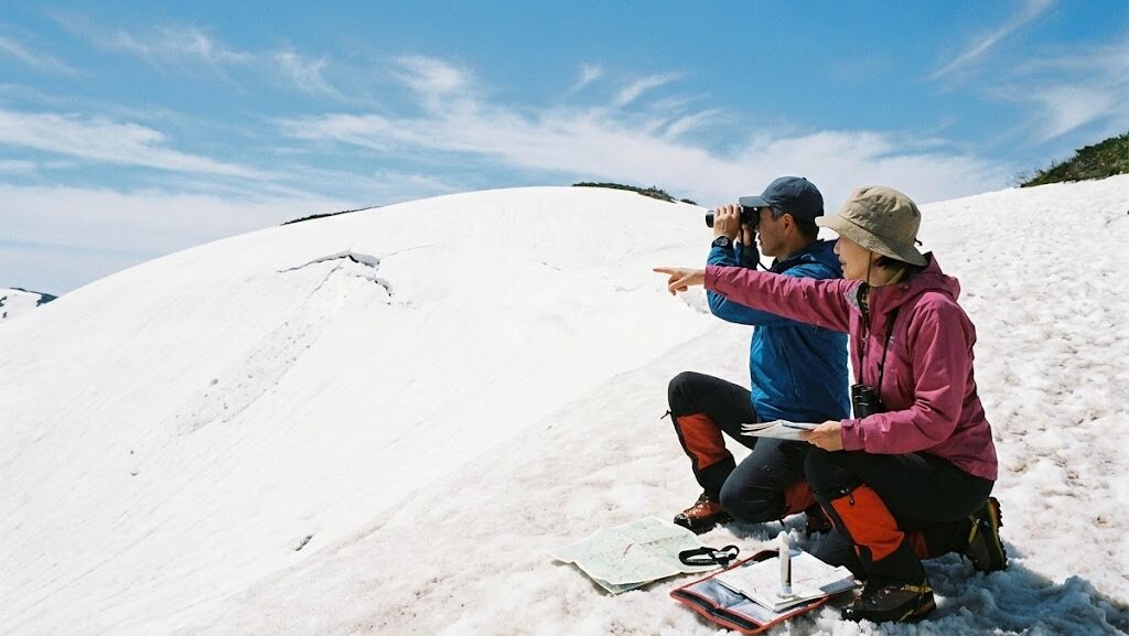 春山で雪面の状態を確認しながら安全に行動する登山者