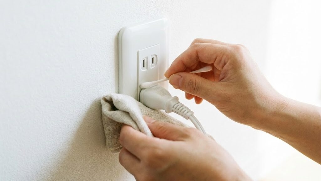乾いた布でコンセント周りを掃除する手元