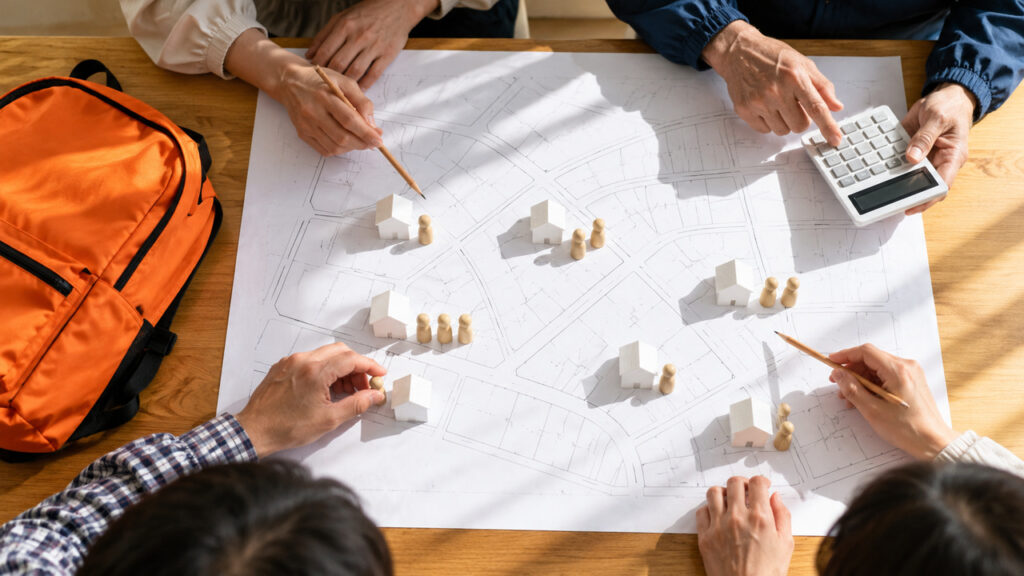 住宅地図と電卓で、世帯数と家族の人数から予算を計算する役員の手元